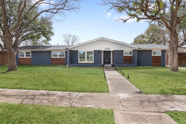 view of front of home with brick siding, a front lawn, and fence