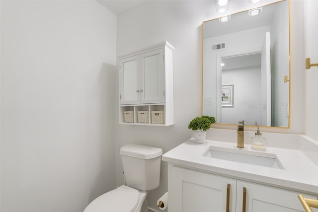 half bath with vanity, toilet, and visible vents