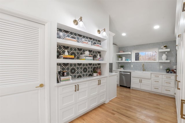 kitchen with open shelves, a sink, stainless steel dishwasher, light wood finished floors, and light countertops