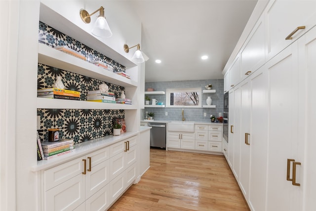 kitchen with open shelves, appliances with stainless steel finishes, light countertops, and a sink