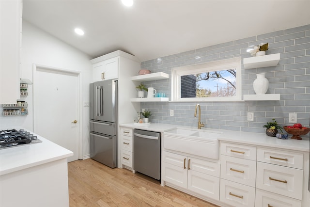 kitchen featuring open shelves, light wood-style flooring, white cabinets, stainless steel appliances, and a sink