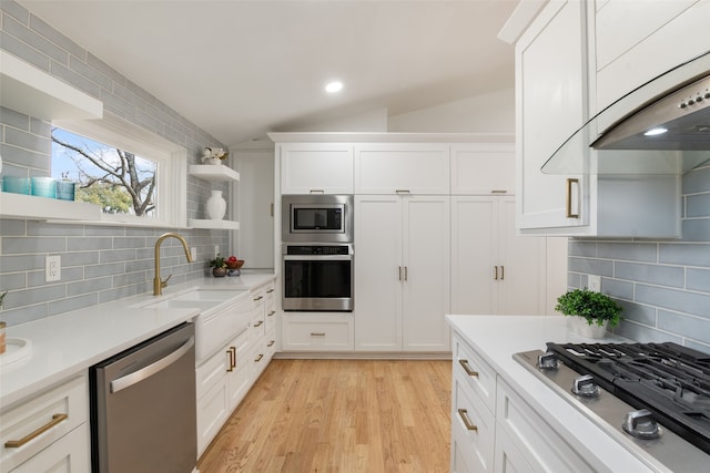 kitchen with open shelves, vaulted ceiling, appliances with stainless steel finishes, white cabinets, and a sink