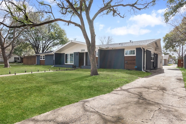 view of front of house featuring brick siding, driveway, and a front lawn