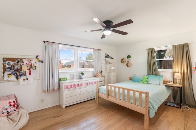 bedroom with baseboards, light wood-style flooring, and a ceiling fan