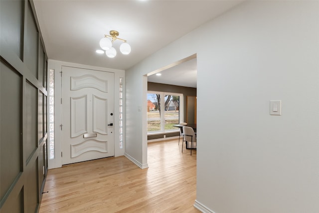 entrance foyer featuring a notable chandelier, light wood-style floors, and baseboards