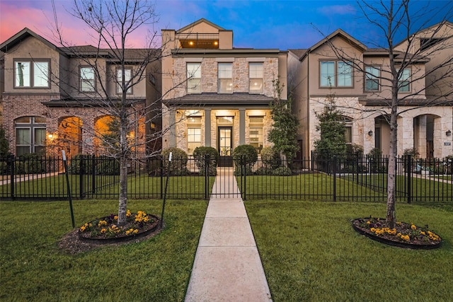 townhome / multi-family property featuring a lawn, stone siding, and a fenced front yard