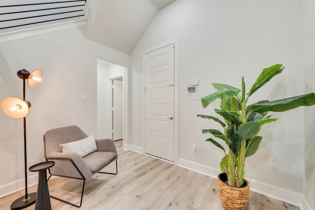 living area with light wood-type flooring, baseboards, and vaulted ceiling