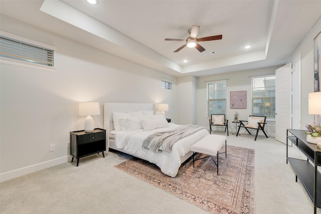 bedroom with visible vents, light carpet, a raised ceiling, recessed lighting, and baseboards