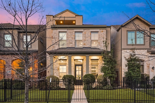 townhome / multi-family property with stucco siding, stone siding, a fenced front yard, and a front yard