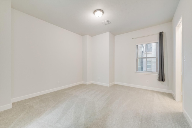 empty room featuring visible vents, baseboards, and light colored carpet