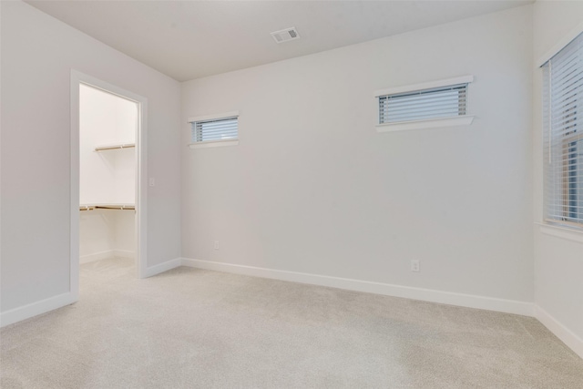 unfurnished room with light carpet, visible vents, and baseboards