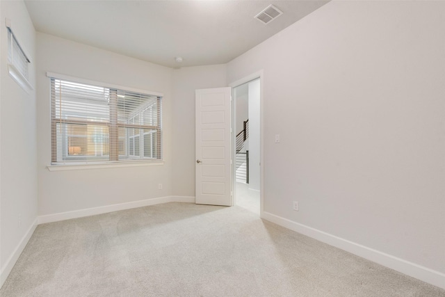 empty room featuring visible vents, baseboards, and light carpet