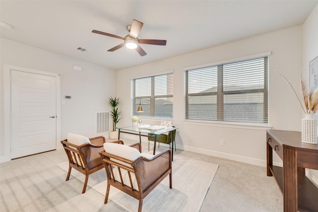 home office with a ceiling fan, light colored carpet, visible vents, and baseboards