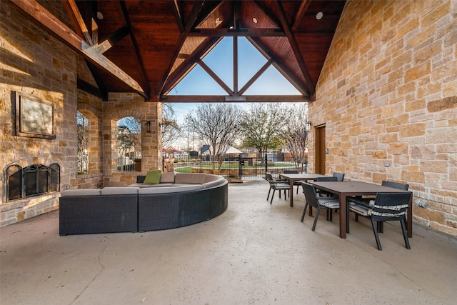 view of patio featuring an outdoor living space with a fireplace, outdoor dining space, and fence