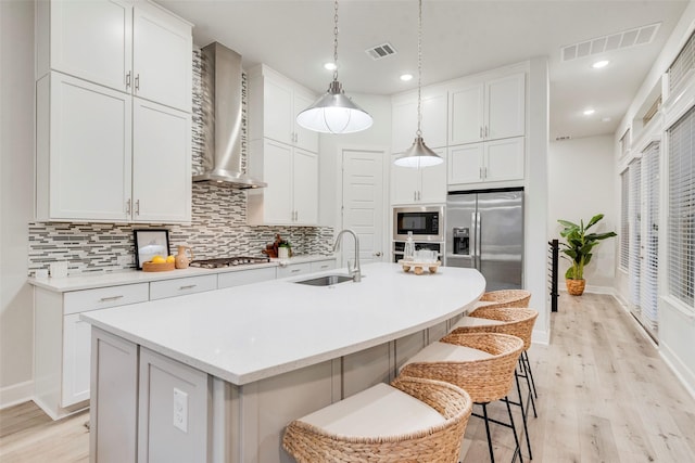 kitchen featuring a sink, visible vents, appliances with stainless steel finishes, and wall chimney exhaust hood