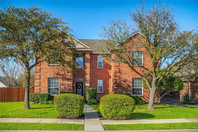 view of front of property featuring a front lawn, fence, and brick siding