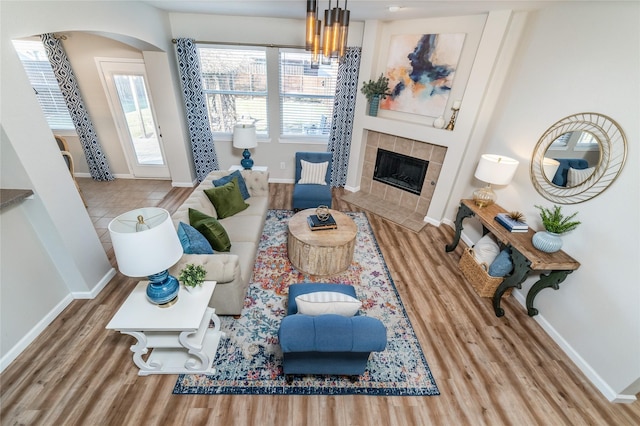 living room with baseboards, arched walkways, wood finished floors, and a fireplace