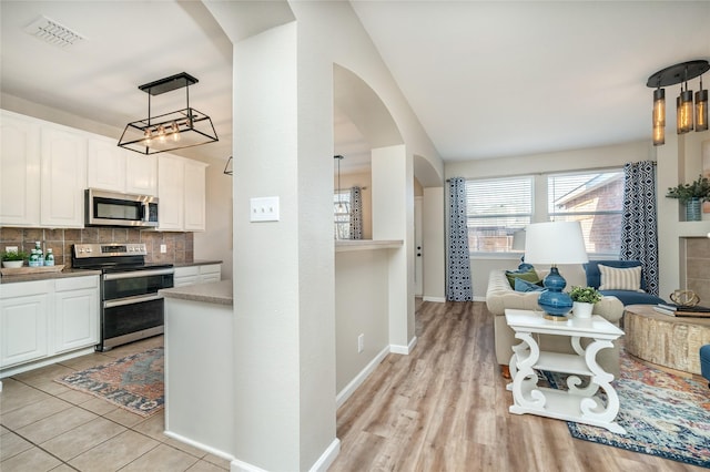 kitchen featuring visible vents, arched walkways, appliances with stainless steel finishes, white cabinetry, and tasteful backsplash