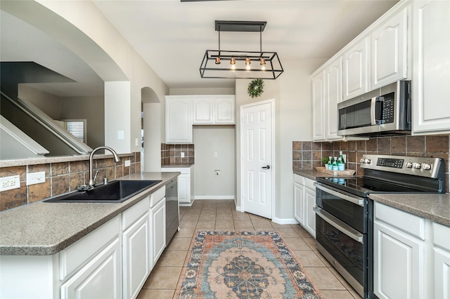 kitchen with white cabinets, light tile patterned flooring, appliances with stainless steel finishes, and a sink