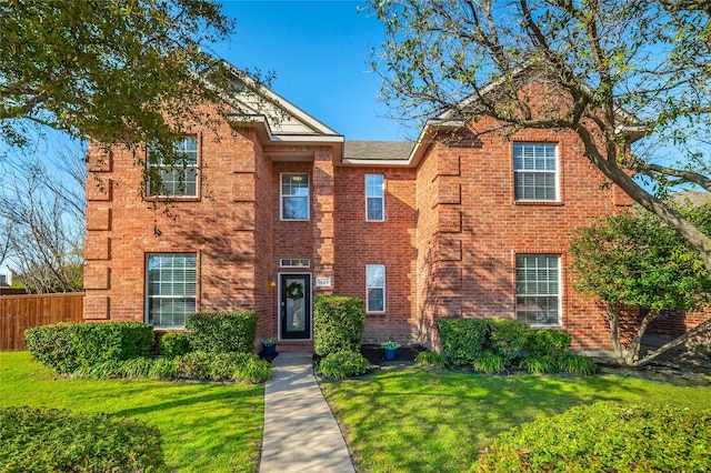 view of front of house featuring brick siding, a front yard, and fence