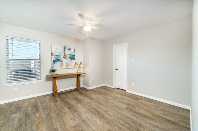 spare room with a ceiling fan, wood finished floors, and baseboards