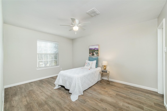 bedroom with visible vents, ceiling fan, baseboards, and wood finished floors