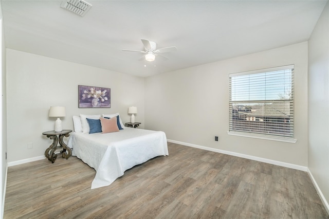 bedroom with wood finished floors, visible vents, and baseboards