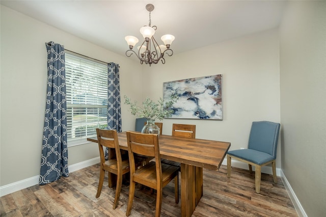 dining area featuring an inviting chandelier, wood finished floors, and baseboards