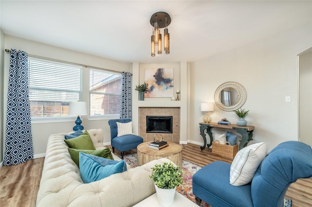 living room featuring wood finished floors, baseboards, and a tile fireplace