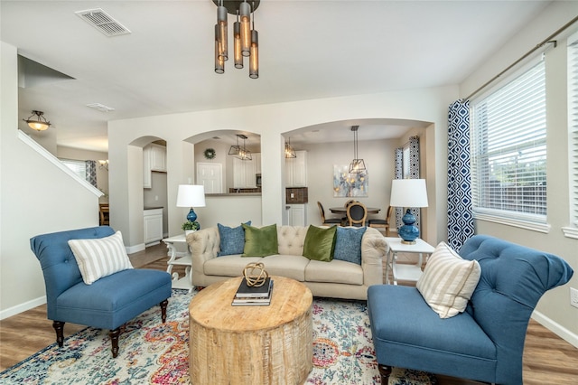 living room featuring visible vents, baseboards, arched walkways, and wood finished floors