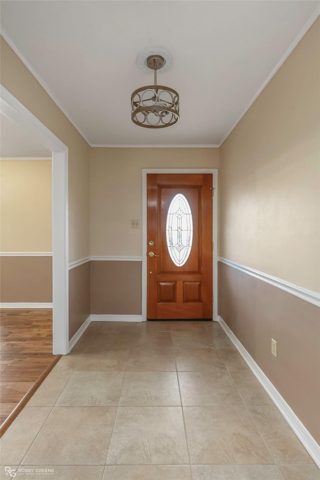 foyer with crown molding, light tile patterned floors, and baseboards