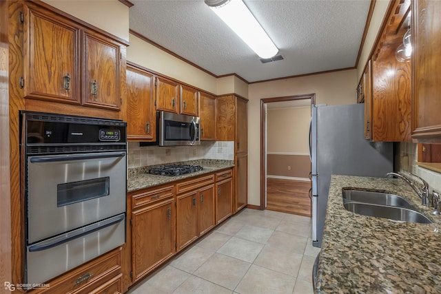 kitchen with visible vents, a sink, stainless steel appliances, a warming drawer, and brown cabinets