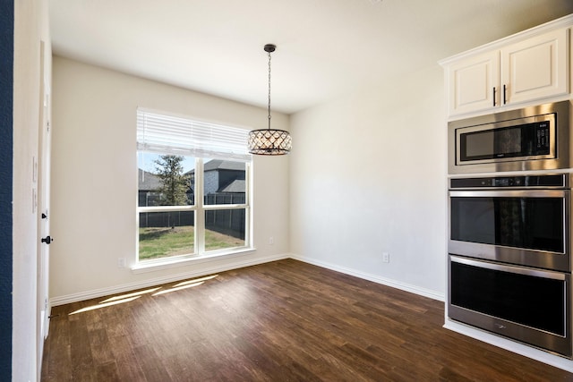 kitchen featuring stainless steel appliances, baseboards, pendant lighting, and dark wood finished floors