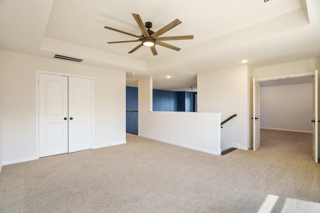 spare room featuring visible vents, ceiling fan, carpet flooring, and a tray ceiling