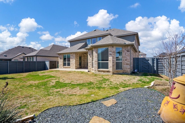 rear view of property featuring brick siding, roof with shingles, a fenced backyard, a patio area, and a gate