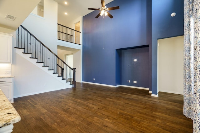 unfurnished living room with stairway, baseboards, dark wood-style flooring, and a ceiling fan