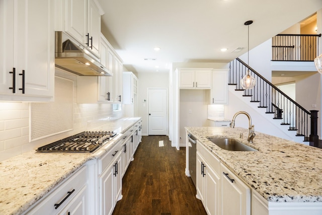 kitchen featuring a sink, under cabinet range hood, appliances with stainless steel finishes, white cabinets, and dark wood-style flooring