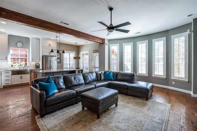 living area featuring visible vents, baseboards, beamed ceiling, and dark wood-style floors