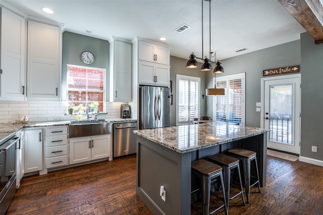 kitchen featuring backsplash, light stone countertops, appliances with stainless steel finishes, dark wood-style floors, and white cabinets