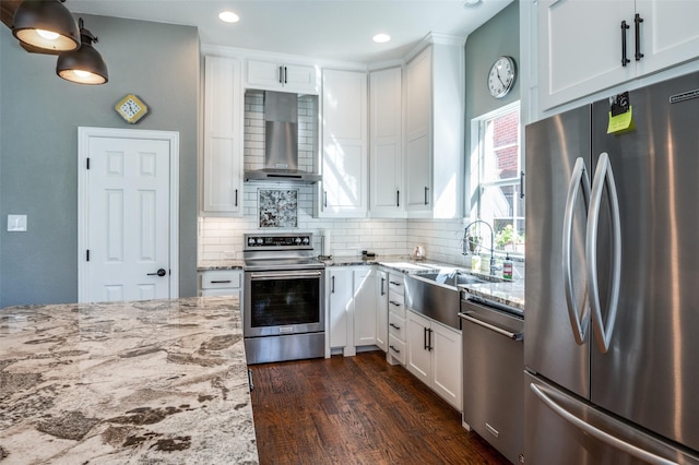 kitchen with a sink, light stone counters, tasteful backsplash, appliances with stainless steel finishes, and wall chimney exhaust hood