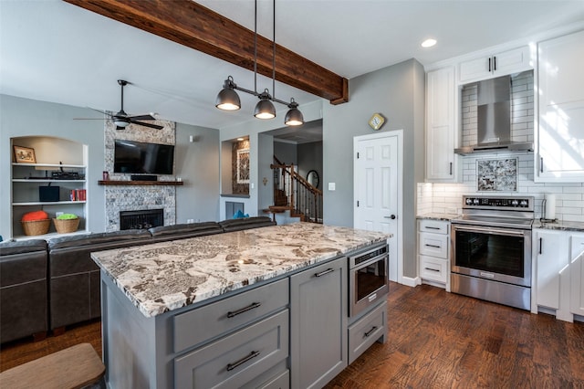 kitchen featuring light stone counters, stainless steel range with electric stovetop, gray cabinetry, and wall chimney range hood