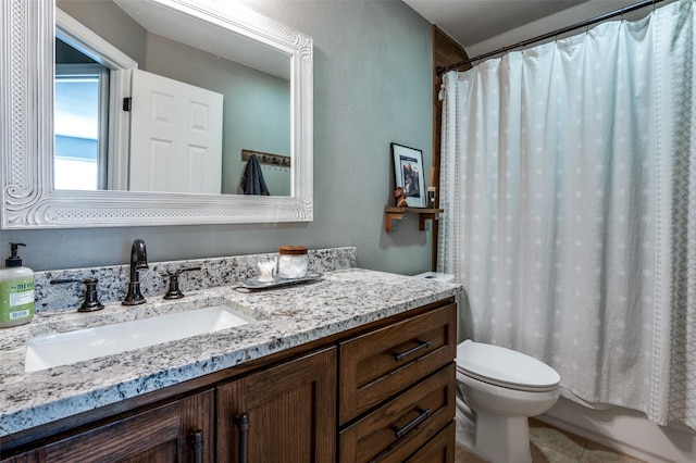 full bathroom with toilet, vanity, and a textured wall