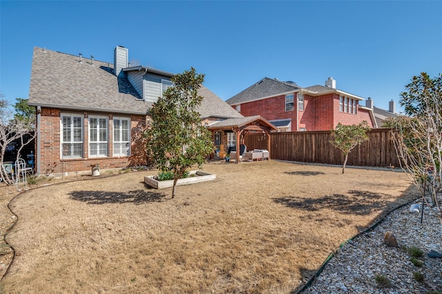 rear view of house featuring brick siding, a shingled roof, a chimney, and fence