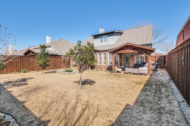 rear view of house featuring a patio, a fenced backyard, a shingled roof, brick siding, and a chimney