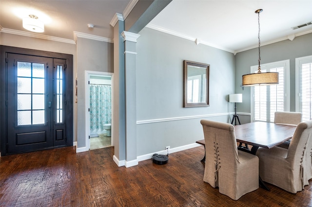 unfurnished dining area with wood finished floors, visible vents, baseboards, decorative columns, and crown molding