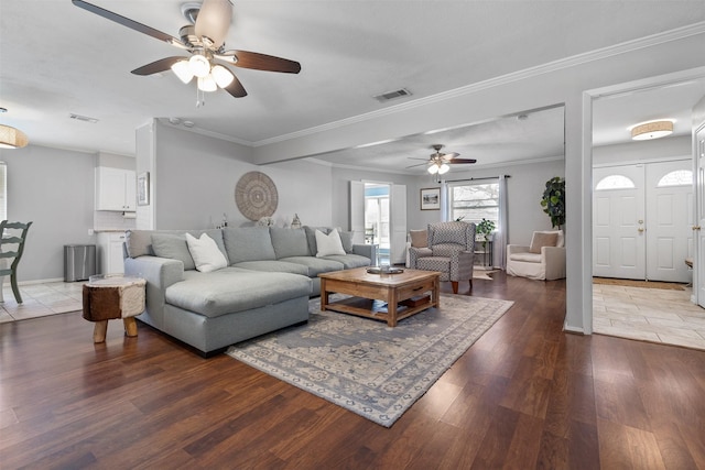 living room with crown molding, wood finished floors, visible vents, and baseboards