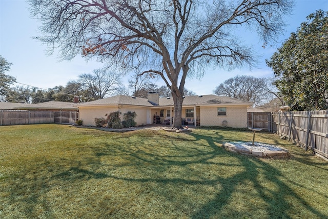 rear view of property with brick siding, a lawn, a chimney, and a fenced backyard