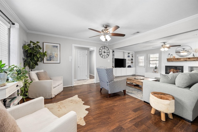 living area featuring a glass covered fireplace, crown molding, wood finished floors, and visible vents