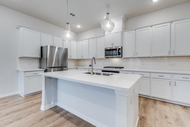 kitchen featuring visible vents, an island with sink, light wood-style floors, stainless steel appliances, and a sink