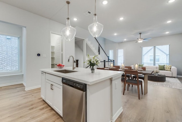 kitchen featuring open floor plan, dishwasher, light wood-type flooring, and a sink